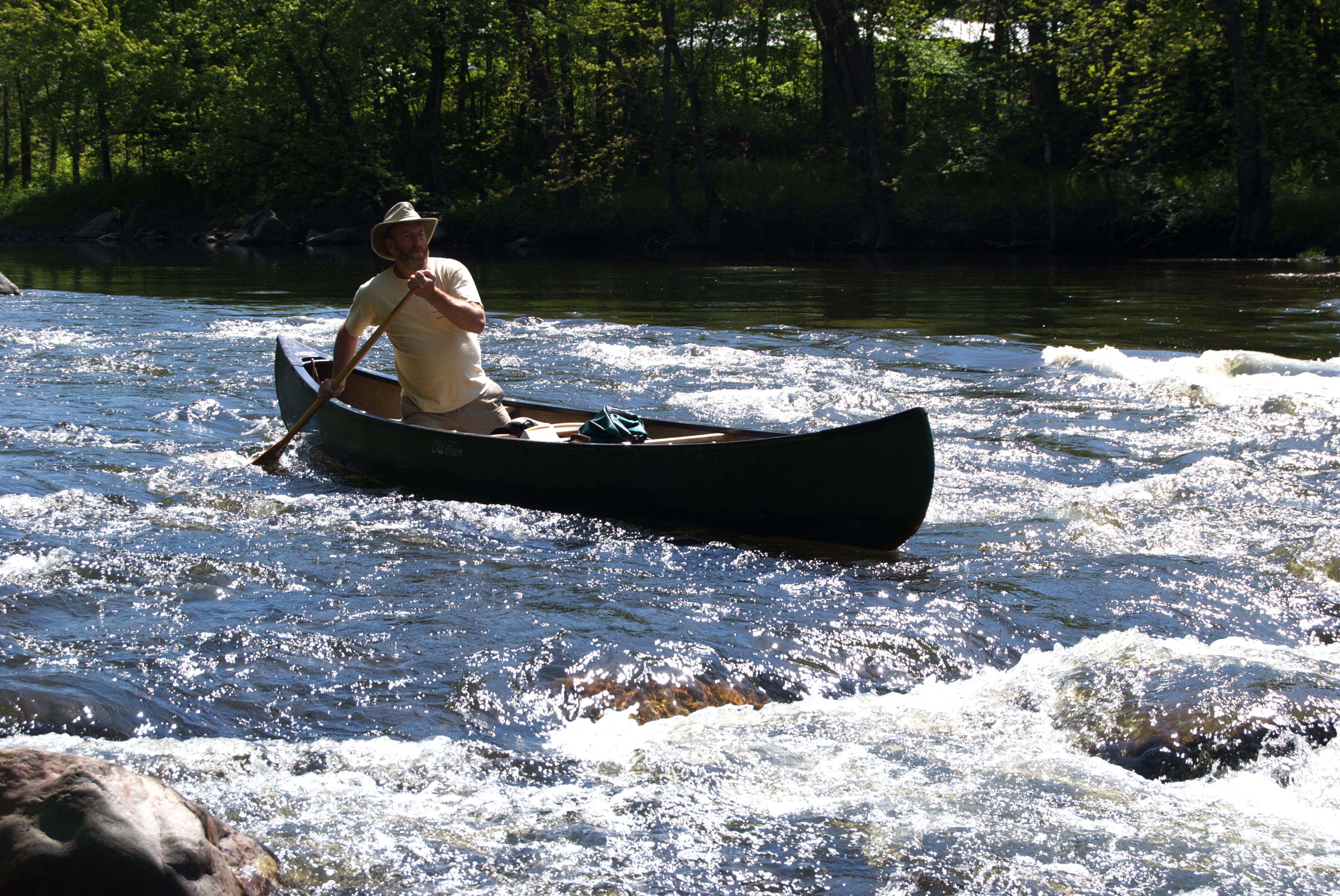 A man is canoeing down rapids in the Missiquoi River, VT. Photo by Ken Secor