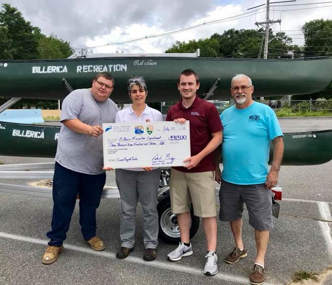 Presentation of a check for the canoe trailer purchase. The canoe trailer sits behind the 4 individuals loaded with canoes. Photo from the Sudbury, Assabet, & Concord Wild and Scenic River Stewardship Council.